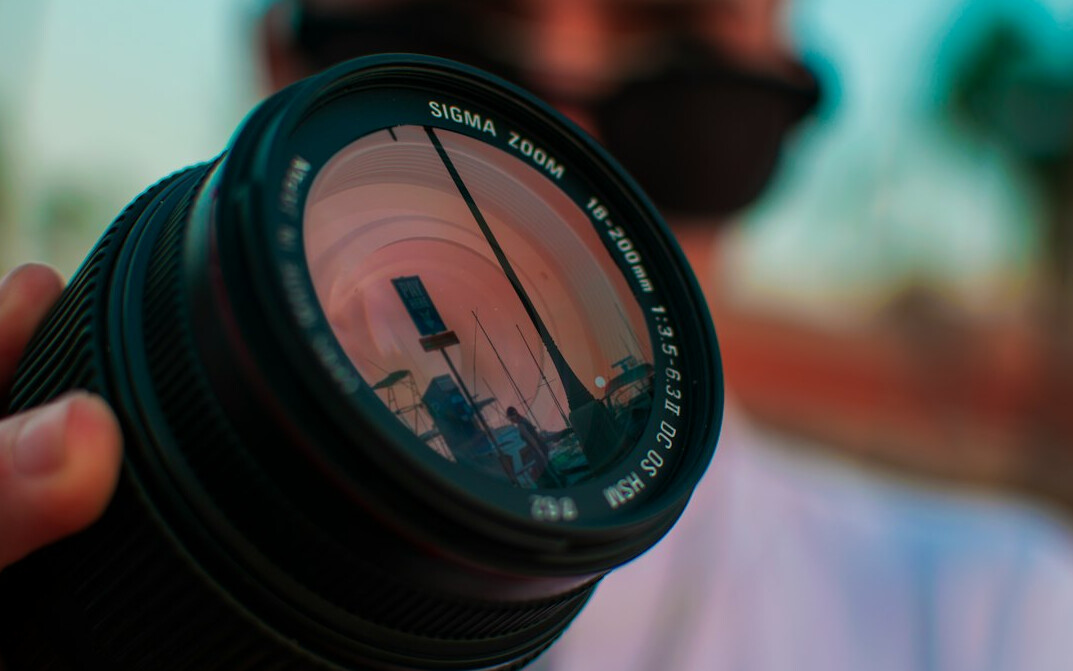 Close-up of a professional camera lens held by a photographer